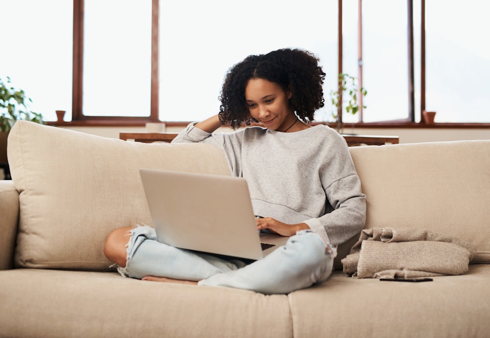 [Featured image] A woman works from home on her couch and uses Google Keyword Planner on her laptop.