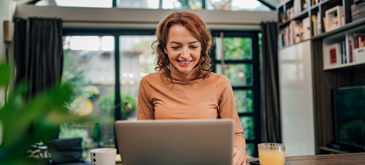 [Featured image] A woman wearing an orange turtleneck sits at home in front of her laptop working on a job application email.