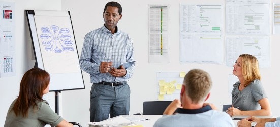 [Imagen destacada] Un experto en marketing SEO presenta un gráfico a un grupo en una mesa de conferencias.