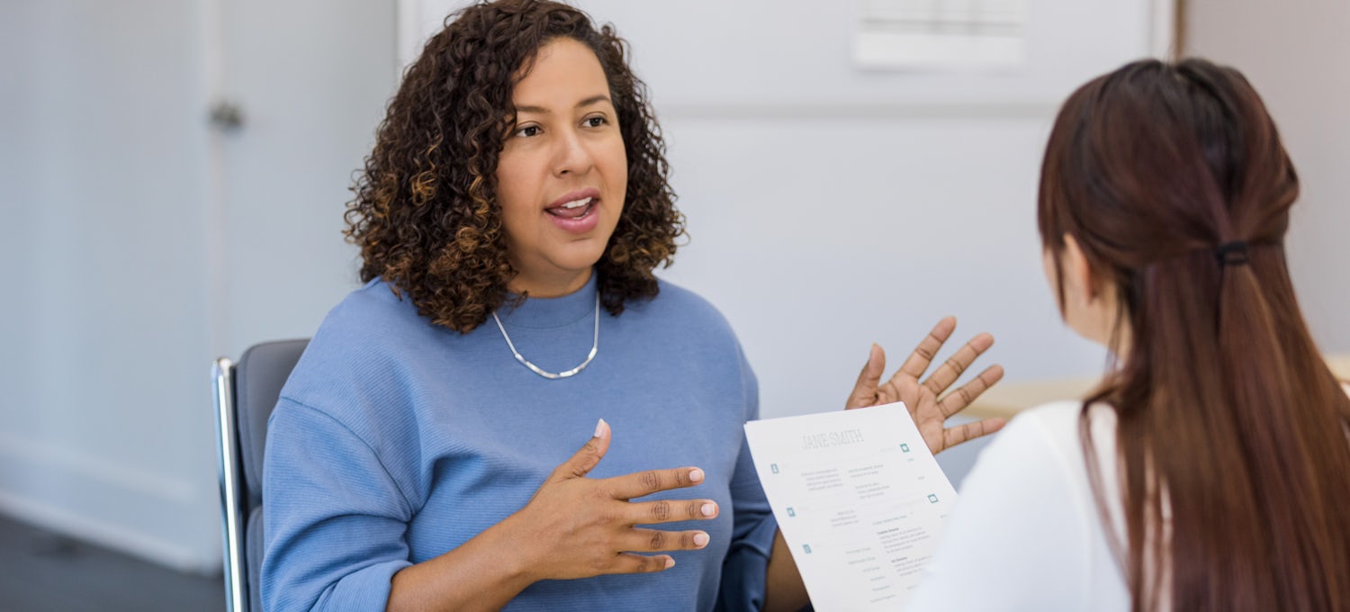 A woman is seen explaining an answer during a job interview.