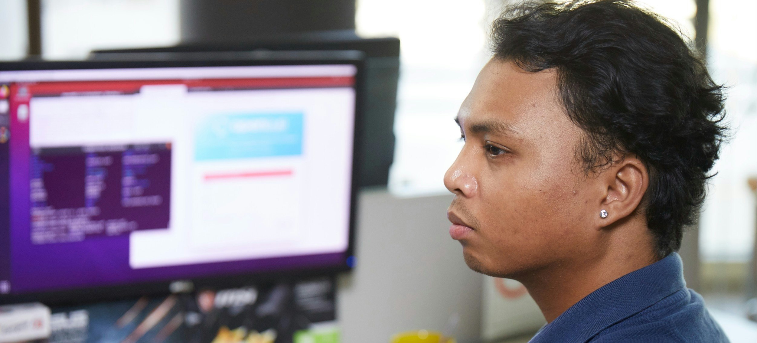 [Featured Image]:  A college student,  wearing a blue shirt and working on a desktop computer, using tools to improve memory. 