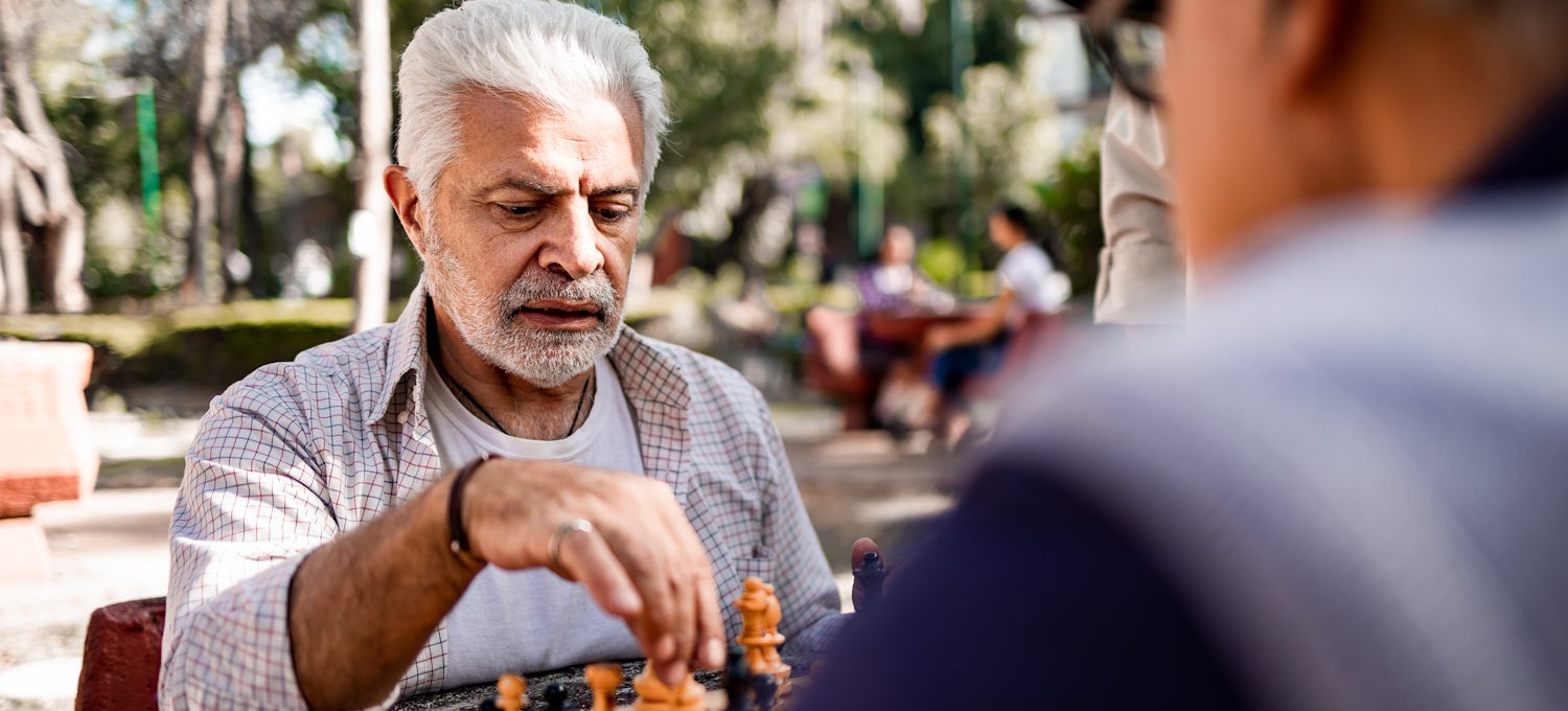 [Featured Image] Two senior men playing chess in the park.
